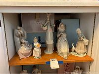 Shelved display showing all five Lladro figurines together, capturing size and relative scale.