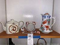 Lot items showing decorative rectangular dragon teapot, tall fish motif teapot, floral picture frame, letter opener, decorative egg