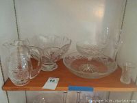 Full view of entire glassware lot on shelf showing pitcher, serving bowls, glasses, candy dish and toothpick holder
