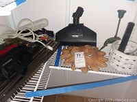 Overview of lot items including vacuum cleaner attachments, terracotta sun decor, white basket with pens and tools