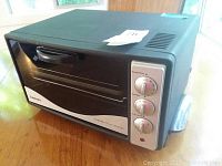Front view of black and silver Cuisinart toaster oven showing door handle and three control knobs