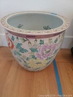 Front view of the planter showing the floral exterior design and curved rim.