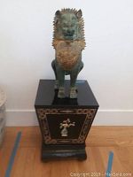 Front view of foo dog statue on lacquered pedestal showing full lot
