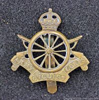 Front view of Army Cyclist Corps WW1 cap badge with crowned wheel design and banner.