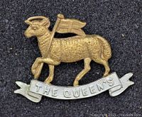 Front view of the Queens Royal West Surrey Regiment brass collar badge showing lamb with flag and banner inscribed with 'THE QUEEN'S'