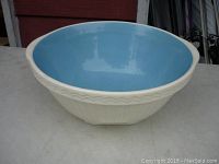 Side angle showing full profile of the antique Easimix mixing bowl with cream exterior and blue glazed interior on a flat surface.