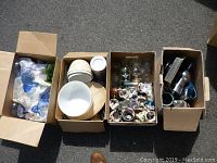 Four boxes containing various decorative and houseware items including glassware, ceramics, and kitchen utensils.