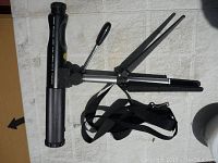 Top view of Bushnell spotting scope mounted on tripod with folded legs visible, strap attached.