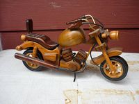 Side view of the carved wooden motorcycle figurine showing detailed features and profile.