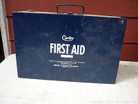 Closed blue Curity metal first aid kit box showing branding and wear on the surface.