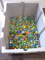 Box filled with assorted glass marbles of different colors and sizes, mostly vintage style.