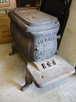 Angled front view of the Herald 125 cast iron stove showing embossed front panel and two round stove plates on top.