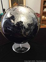 Globe showing Asia, with black ocean and silver countries on chrome base