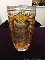 Front angled view of amber crystal vase showing etched floral designs and ridged clear rim.