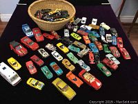 Wide view of entire toy car collection arranged on a surface with basket containing additional cars.