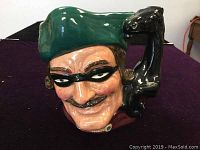 Front close-up of the vintage Royal Doulton Toby Jug featuring Dick Turpin's face with a green hat and black eye mask.