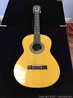 Front view of vintage acoustic guitar with visible single broken string and natural wood finish.