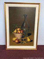 Full view of the framed still life oil painting with fruit, carafe, and glass.