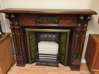 Full front view of mantel showing overall assembly including wood surround, metal insert and tile panels