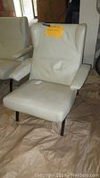 Front three-quarter view of off-white leather chair showing overall design and condition