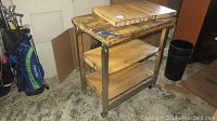 3-tier metal and wood rolling cart with visible wear and a wooden butcher block placed on top
