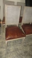 Front view of a single chair showing leather seat and cane back