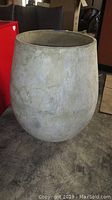 Full view of the oversized vase standing on a floor, neutral earth-toned pottery with textured finish.