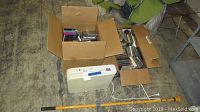 Photo showing paper shredder, cardboard boxes with CDs, and telescoping lightbulb changer pole on concrete floor