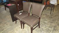 Pair of brown leather chairs with studded trim viewed from front and side angles, showing some wear and marks on the seat cushions and backs.