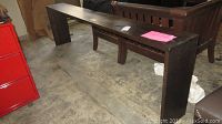 Full view of the long side table showing the dark wood look finish and rectangular shape with visible scratches and marks.