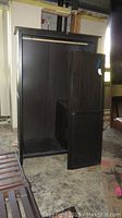 Large dark wood wardrobe unit with doors leaning against it, showing front view