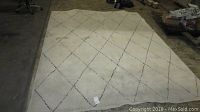 Full view of the 8x10 Kazbar area rug, cream color with black diamond lattice pattern, visible heavy soiling