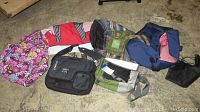 Seven assorted travel bags laid on the ground including floral, striped, and solid color designs.