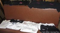 Full view of 9 chef jackets laid out showing different colors and embroidered names including 'Distrito' and individual chef names