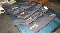 Six black chef jackets folded and displayed on a table with embroidered 'Jose Garces' and Kbas Night logos visible on each.
