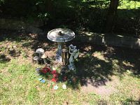 Concrete bird bath with floral embellishments, angel statue holding bowl, wind chime, mushrooms, metal turtles and frog, red flower and ceramic tile ground decor