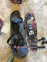 Top view of snowshoes, poles, and carrying bag arranged on concrete floor