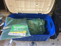 Blue Rubbermaid storage container with green woven polyethylene tarpaulins inside, lid open
