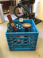 Blue plastic crate containing red hydraulic Porta Power and house jack from side view.