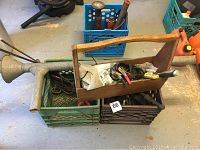 Wooden toolbox packed with tools and cables, an old metal oil can, and a visible orange electric heat source.