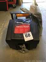Front view of the Master Lock electric winch showing the hook, cable coiled on top, and red and black Master Lock label with product info.