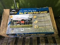 Original packaging box front showing ShelterLogic branding, canopy image and size