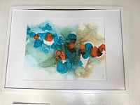 Frontal photo of the abstract alcohol ink painting showcasing blue, orange, and tan hues framed with white matting.