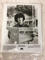 Black and white 8x10 promotional photo featuring Winona Ryder holding a newspaper with headline 'Roxy Returns'