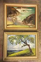 Two framed paintings hung vertically showing a nude figure on a beach above and a tree on a hill below