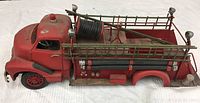 Front and side view of the red decorative toy fire truck showing metal ladders, hose, and detailed features.