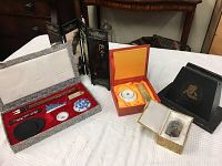 Wide view of five Asian items arranged on white fabric including a wooden display case, seal stamp box, ceramic items, and fabric-lined case with brushes and ink stone.