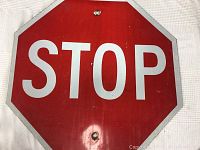 Close-up photo showing the stop sign's front surface with visible mounting holes and wear marks