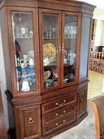 Front view of wooden china cabinet with glass doors displaying various dishes and glassware inside.