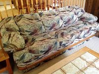 Full view of the Palliser four-seat couch showing patterned fabric cushions and wooden base.